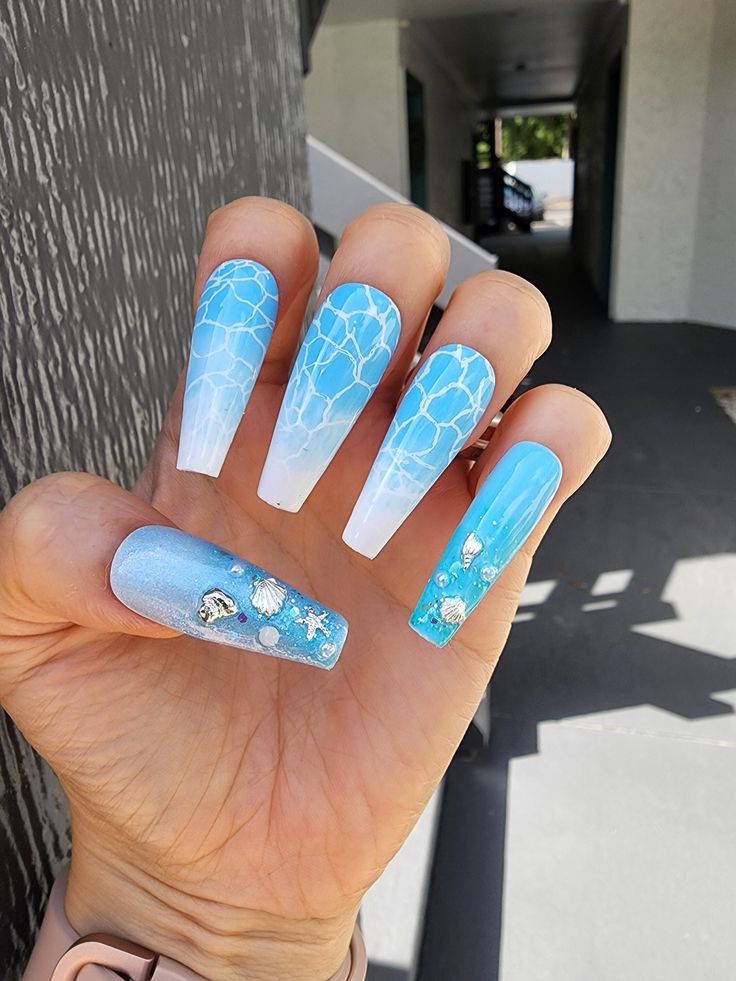 Stunning Ocean-Inspired Nail Art: Gradient Blues with Intricate Wave Patterns and Aquatic Embellishments.