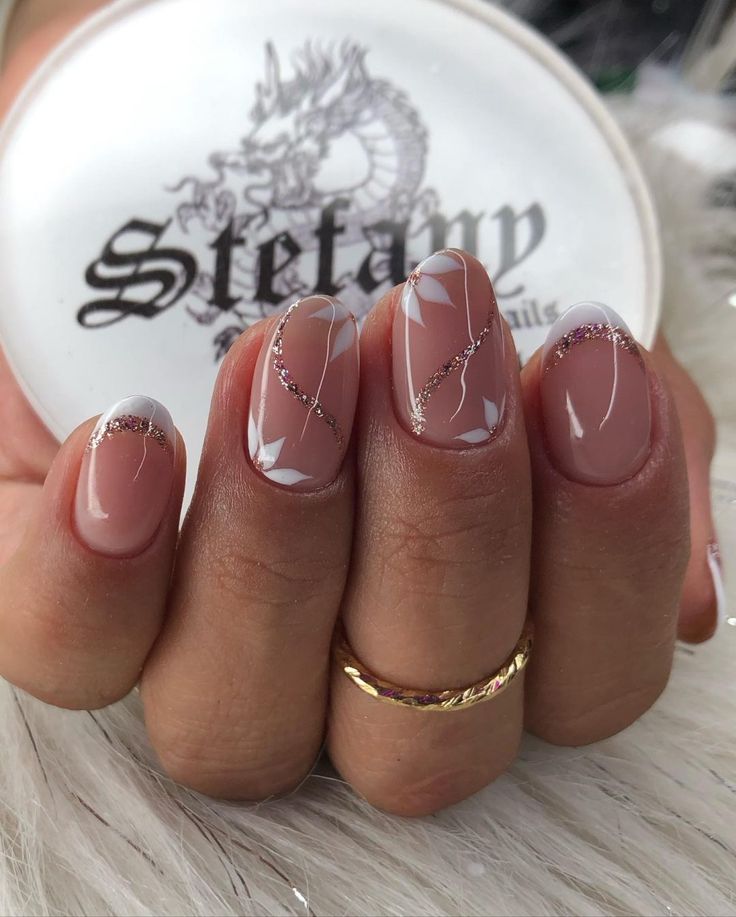 Sophisticated Nail Design: Nude Shades with White Accents and Glamorous Gold Glitter Lines.