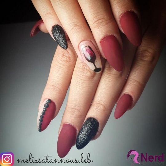 Sophisticated Elegance: Deep Burgundy Stiletto Nails with Playful Wine Glass Art and Rhinestone Accents.