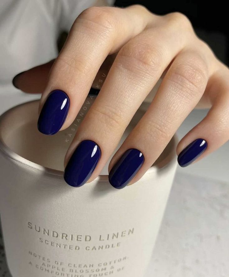 Chic Deep Blue Nails with Glossy Finish on a Neutral Background.