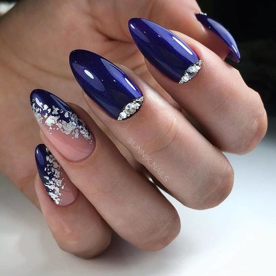 Elegant Deep Blue Glossy Stiletto Nail Design with Rhinestones and Silver Glitter Gradient.