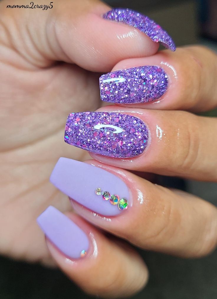 Vibrant Purple Sparkly Nail Design with Glitter and Accent Stones.