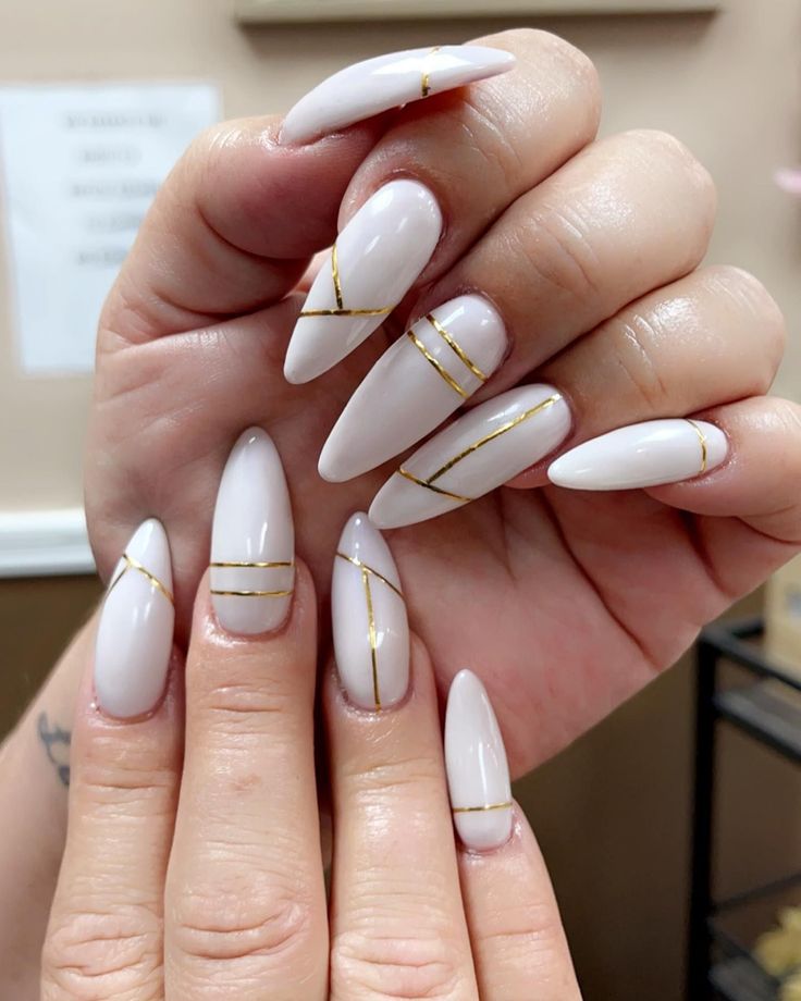 Elegant Almond-Shaped Nails with Sophisticated Gold Striping in Soft White.