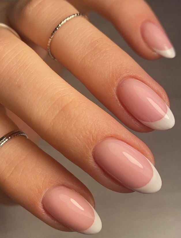 Timeless Elegance: Soft Pink French Tip Nails Accentuated by Silver Rings.