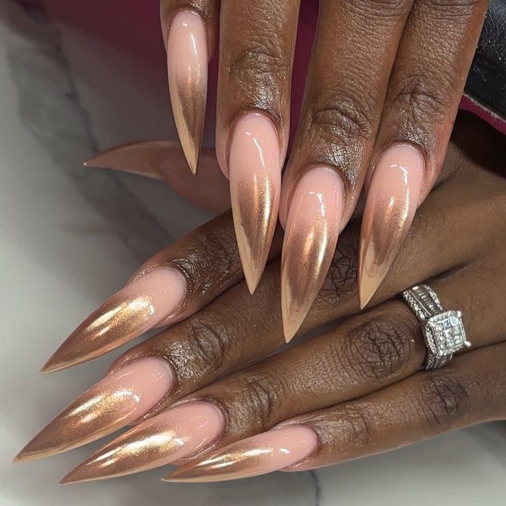 Elegant Ombre Stiletto Nails in Nude and Rose Gold with Glossy Finish and Chic Ring.