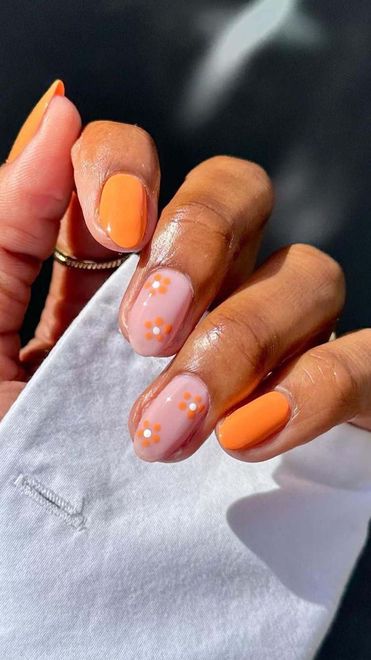 Vibrant Orange and Soft Nude Floral Nail Design: A Whimsical Yet Elegant Spring Look.