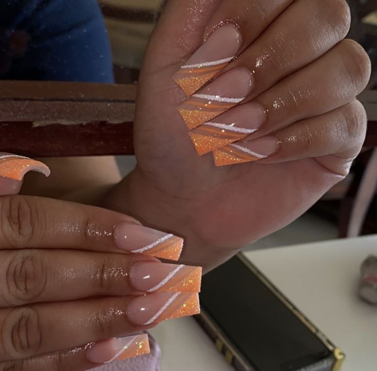 Playful Sophistication: Vibrant Peach and Glittery Orange French Nail Design with White Stripes.