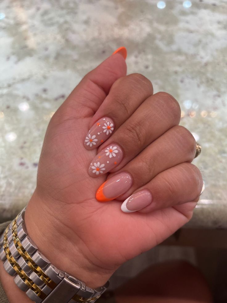 Delightful Floral Nail Design with Soft Nude and Vibrant Orange Hues.