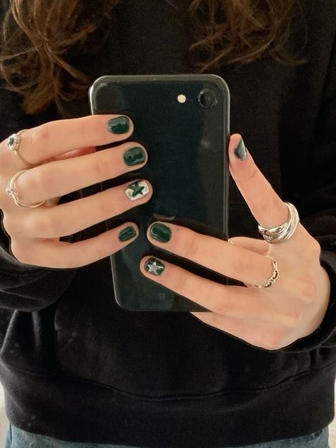 Trendy Dark Green Nail Design with Silver Star Accents and Casual Outfit.