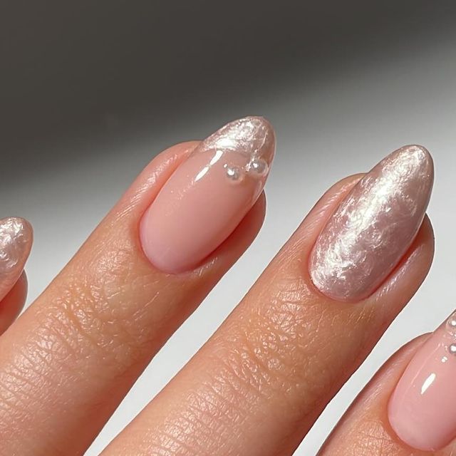 Sophisticated Soft Pink Nail Design with Iridescent Accents and Glamorous Details.