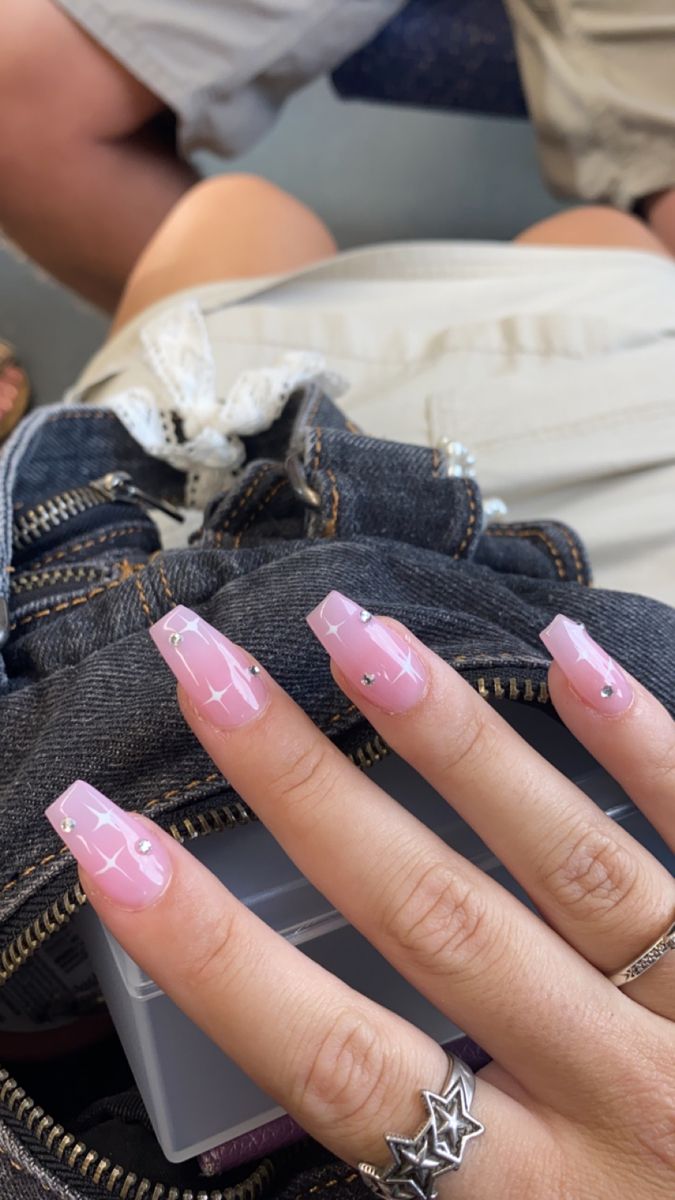 Chic Soft Pink Nail Design with Starry Patterns and Glamorous Rhinestone Accents.