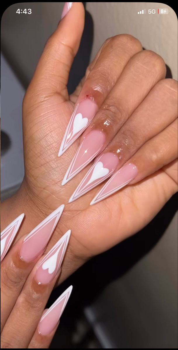 Chic Heart-Adorned Stiletto Nails in Soft Pink and White for a Playful Look.