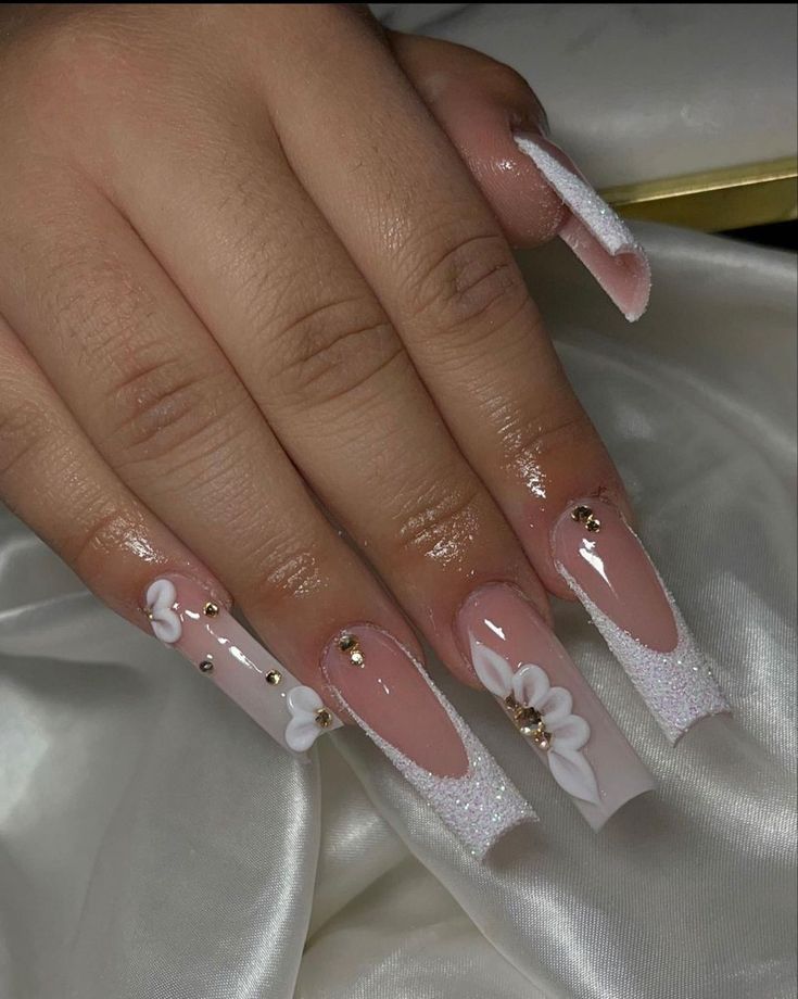 Sophisticated Long Squared Nail Design with Nude Base, Floral Accents, and Rhinestone Glam.