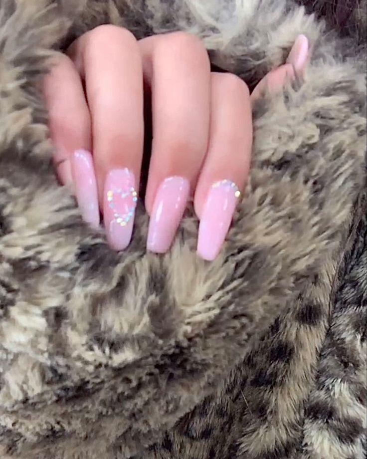 Elegant Long Oval Nail Design with Soft Pink Polish and Subtle Sparkles on Cozy Textured Background.