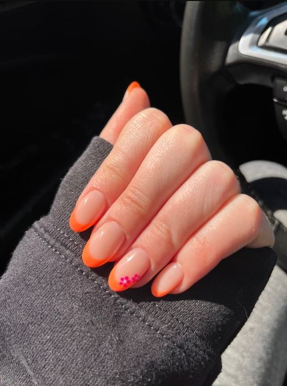 Vibrant Bright Orange French Tips with Playful Pink Accents for Spring and Summer Nail Designs.