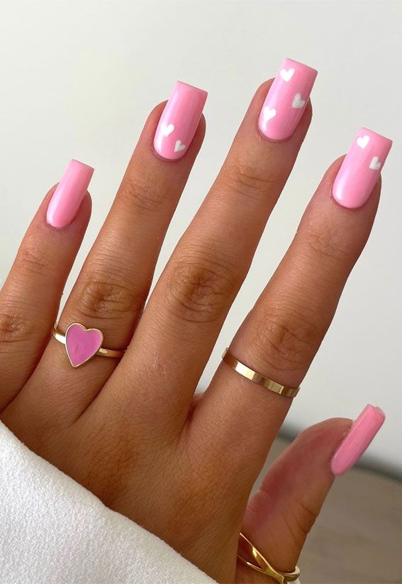 Playful Pink Nail Design with White Hearts and Chic Gold Accents.