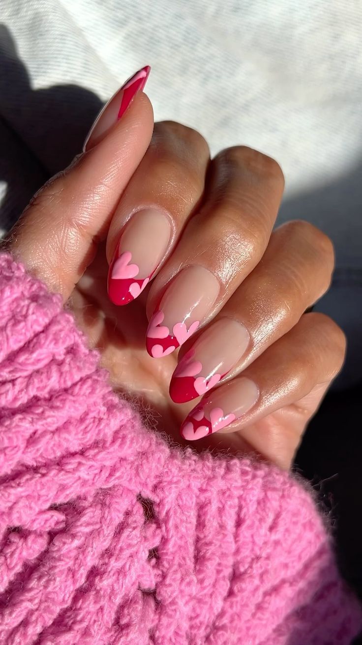 Charming Heart-Themed Nail Design: Soft Nude Base with Vibrant Red Tips and Delicate Pink Hearts.