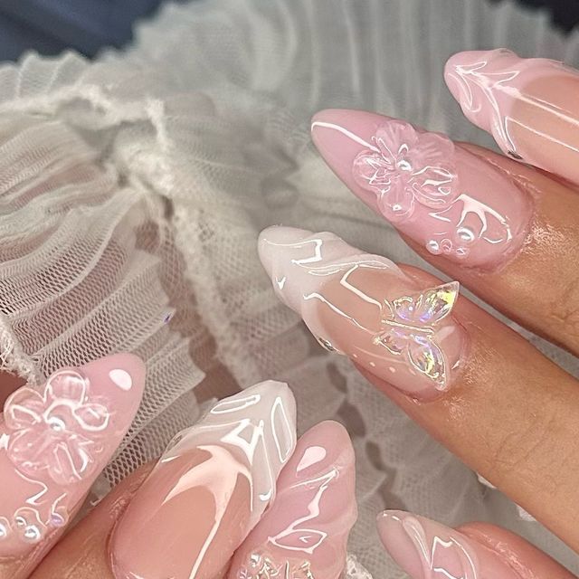 Sophisticated Soft Pink Nail Design with 3D Floral Embellishments and Iridescent Accents.