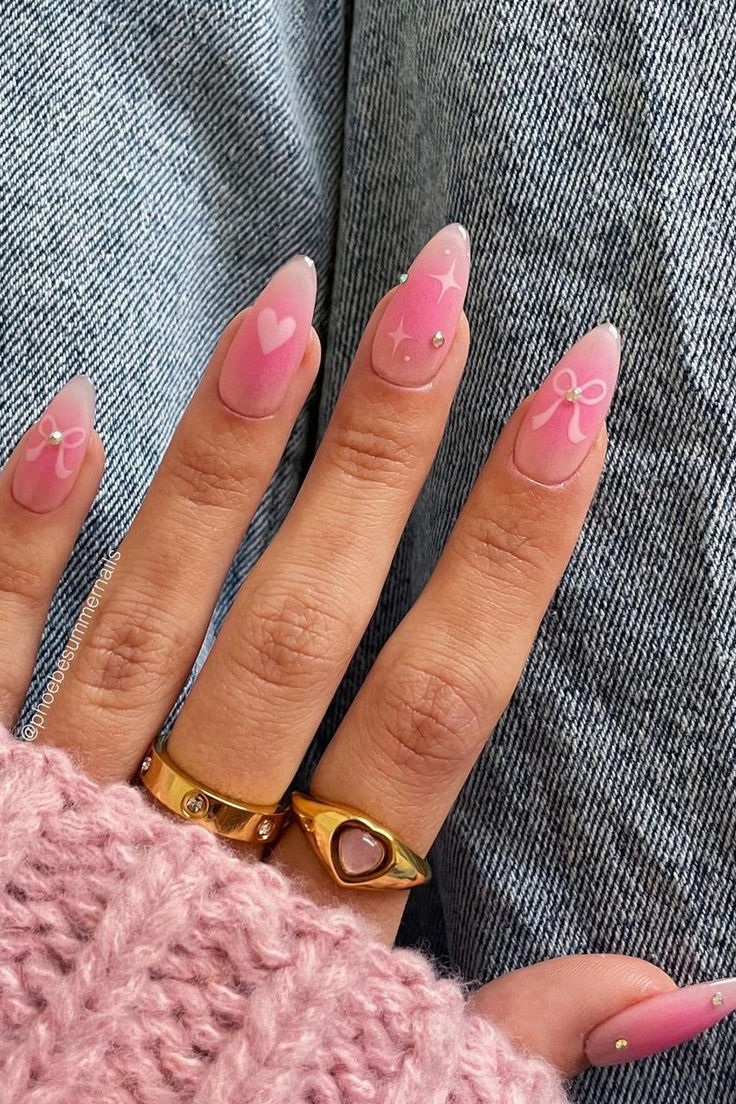 Whimsical Pink Ombre Nails with Hearts and Bows: A Romantic and Glamorous Trend.