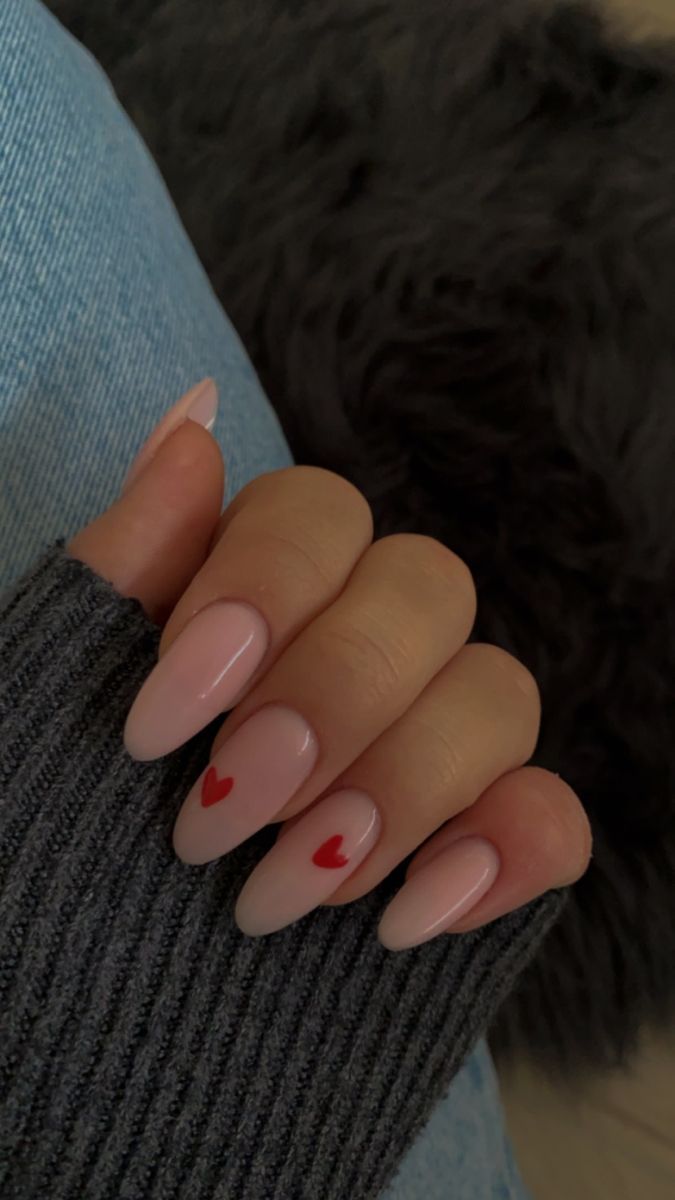 Elegant Almond-Shaped Nails with Nude Polish and Playful Heart Accents.