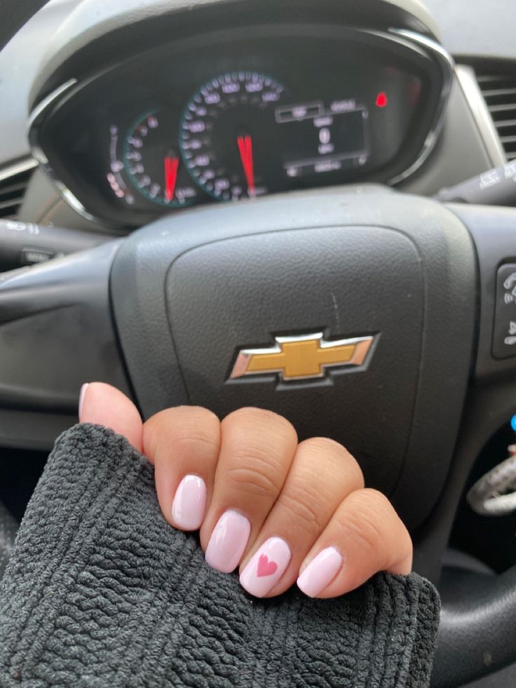 Chic Pink Nail Design with Playful Heart Accent in Stylish Car Interior