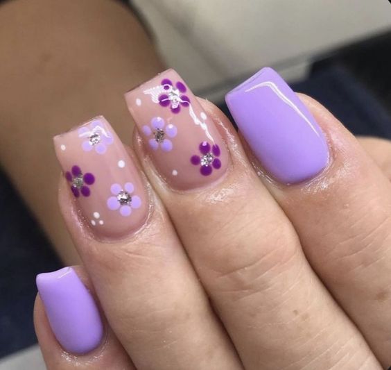 Charming Floral Nail Design with Light Purple and Nude Tones Enhanced by Sparkling Gems.