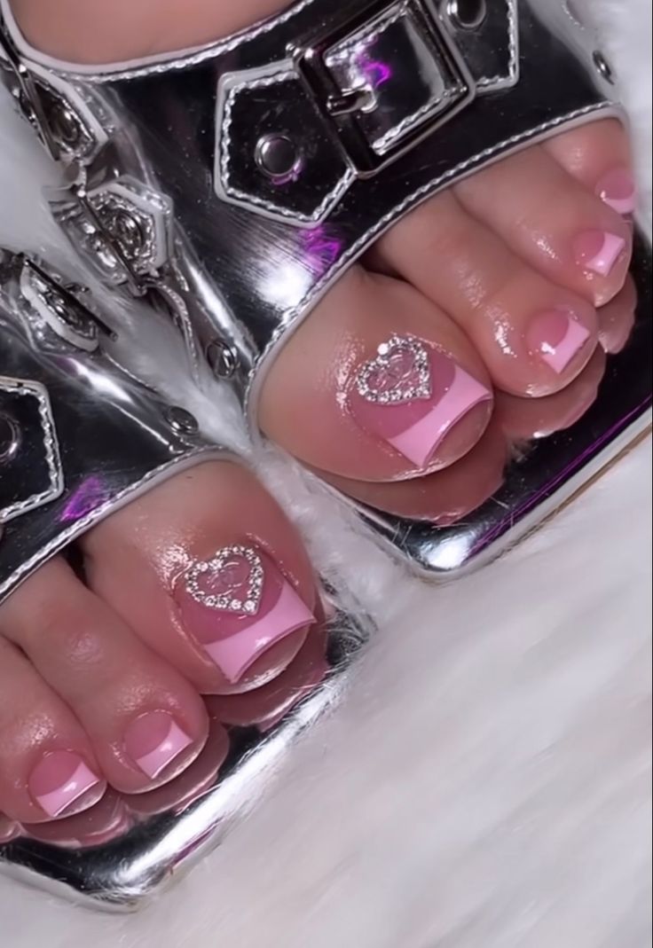 Elegant Soft Pink Pedicure Design with Heart Shapes and Rhinestones, Paired with Metallic Sandals.