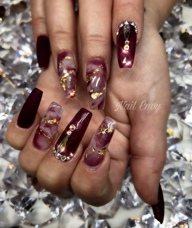 Sophisticated Nail Design: Deep Burgundy Marble with Rhinestones and Gold Accents.