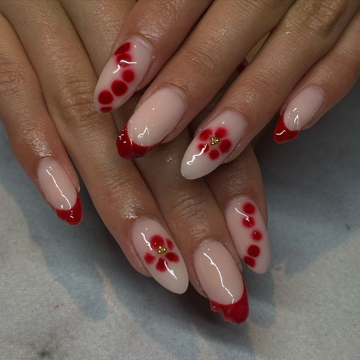 Elegant Nude and Vibrant Red Nail Design with Floral Accents and Golden Embellishments.