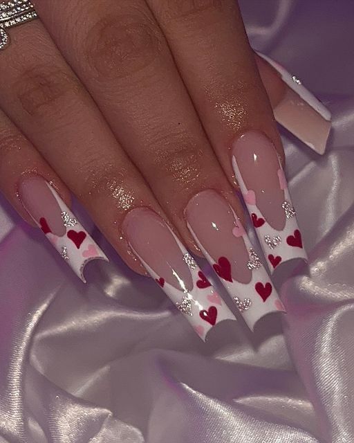 Romantic Heart-Themed Nail Design with Nude Base, Striking White Tips, and Glittering Accents