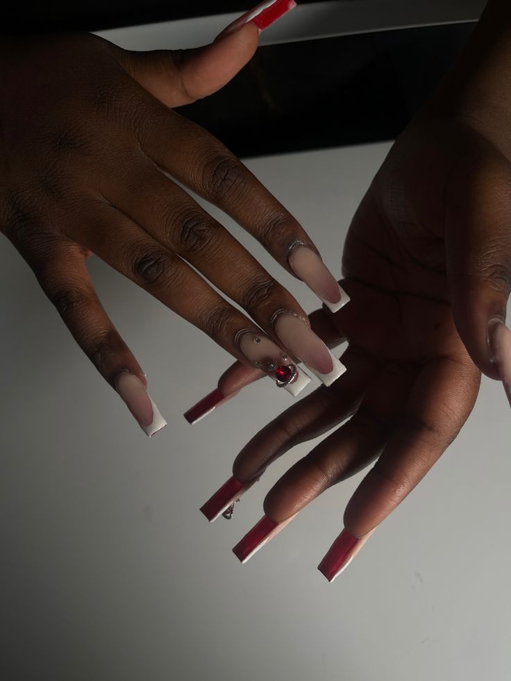 Chic Long Tapered White and Red Nail Design with Eye-Catching Gem Embellishment.