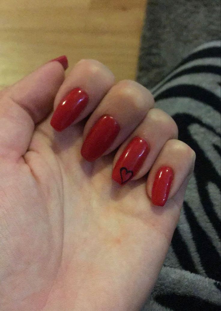 Elegant Red Nails with Charming Black Heart Accent: A Bold Statement for Any Occasion