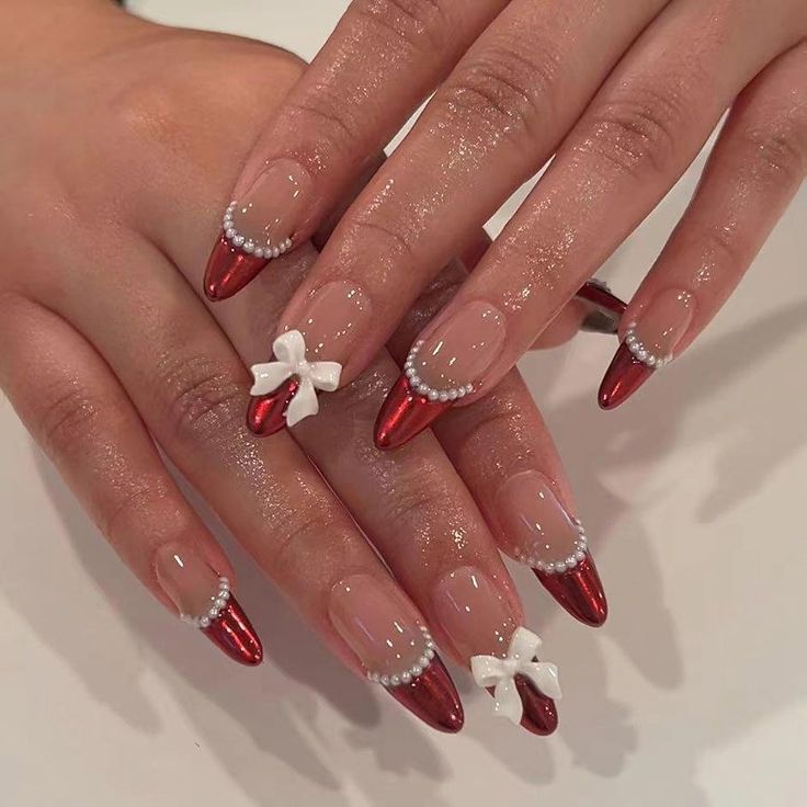 Chic Holiday Nail Design: Glossy Red with Elegant Bows and Pearl Accents.