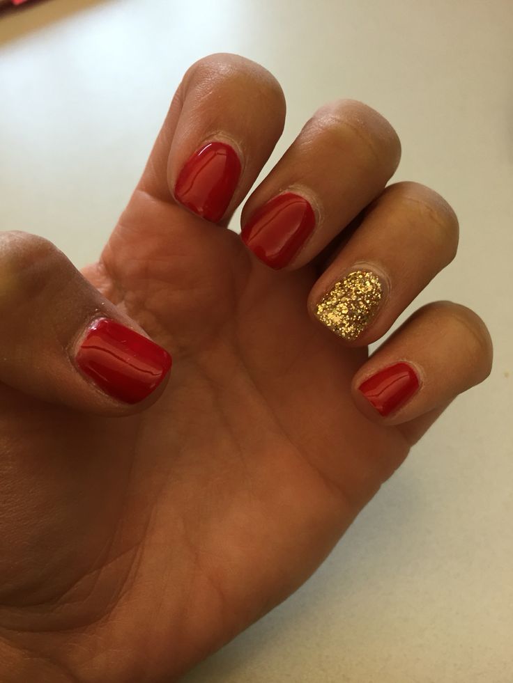 Glamorous Red Manicure Featuring a Chic Gold Glitter Accent.