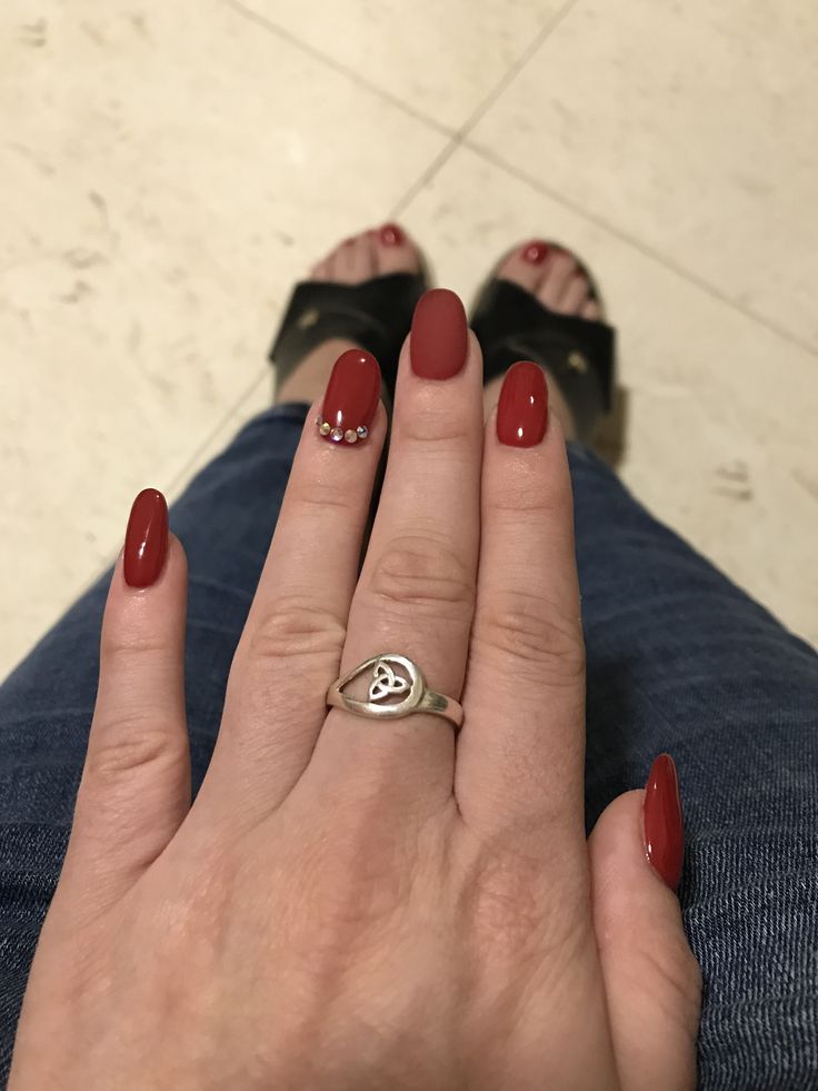 Elegant Red Manicure with Glamorous Rhinestone Accent on Oval Nails