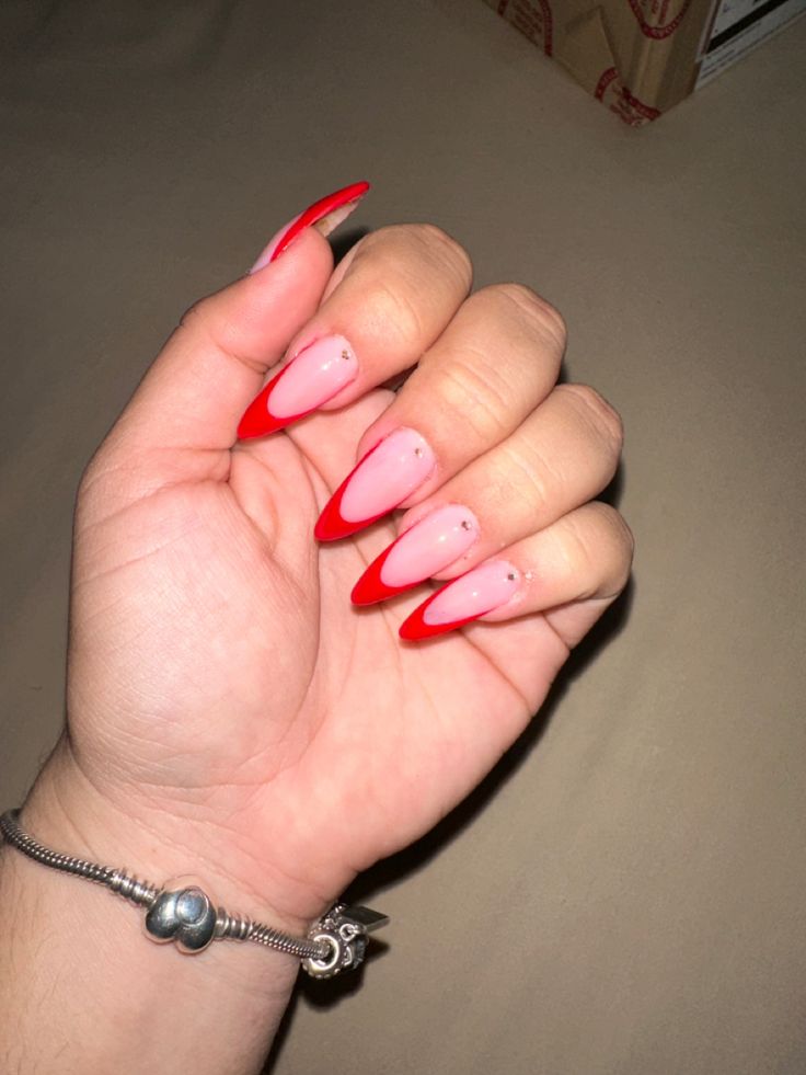 Glamorous Ombre Nail Design: Pink to Red with Elegant Embellishments.