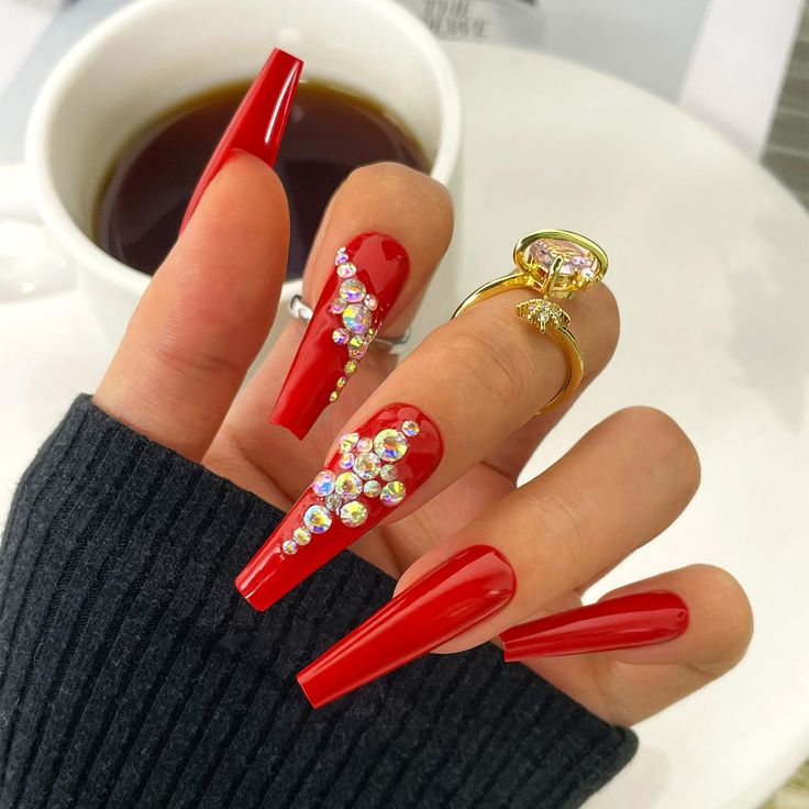 Glamorous Red Acrylic Nail Design with Rhinestones for Special Occasions.