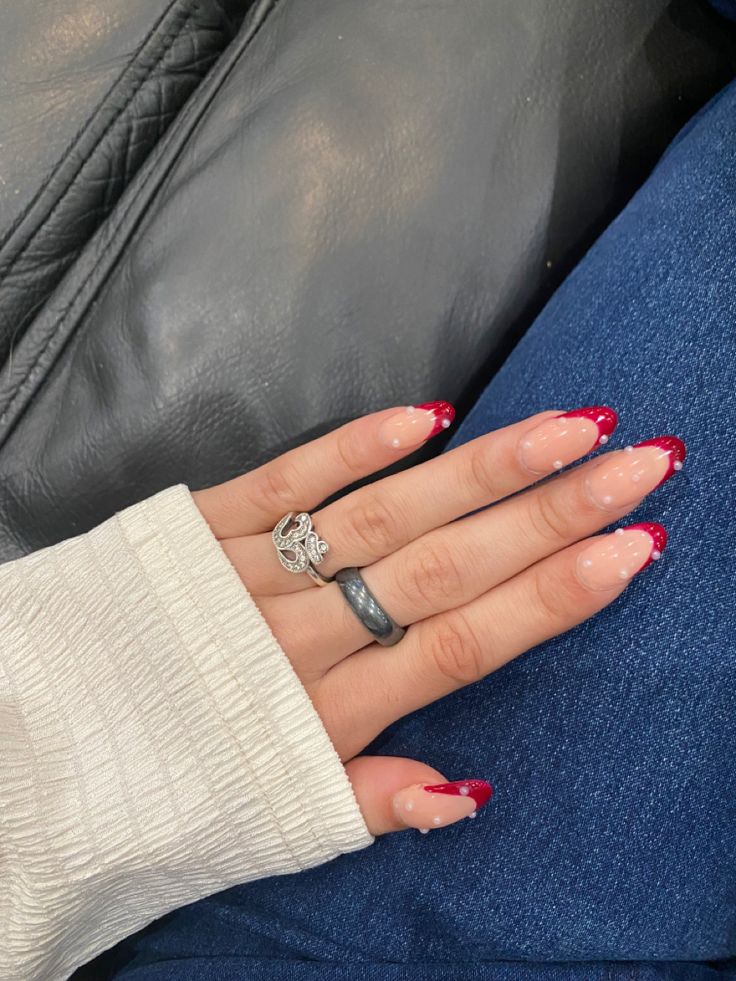 Chic French Tip Nail Design: Vibrant Red Tips with Playful White Dots on Light Pink Base.