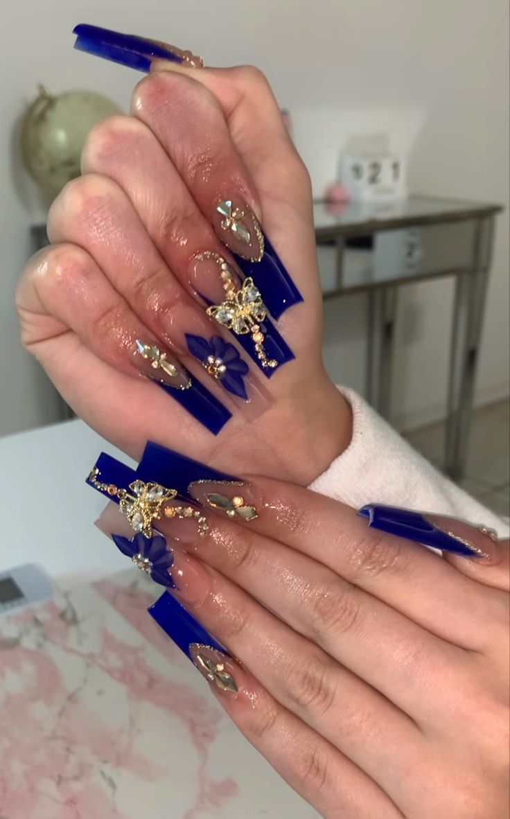 Luxurious Blue Nail Design with Pointed Tips and Gemstone Detailing.