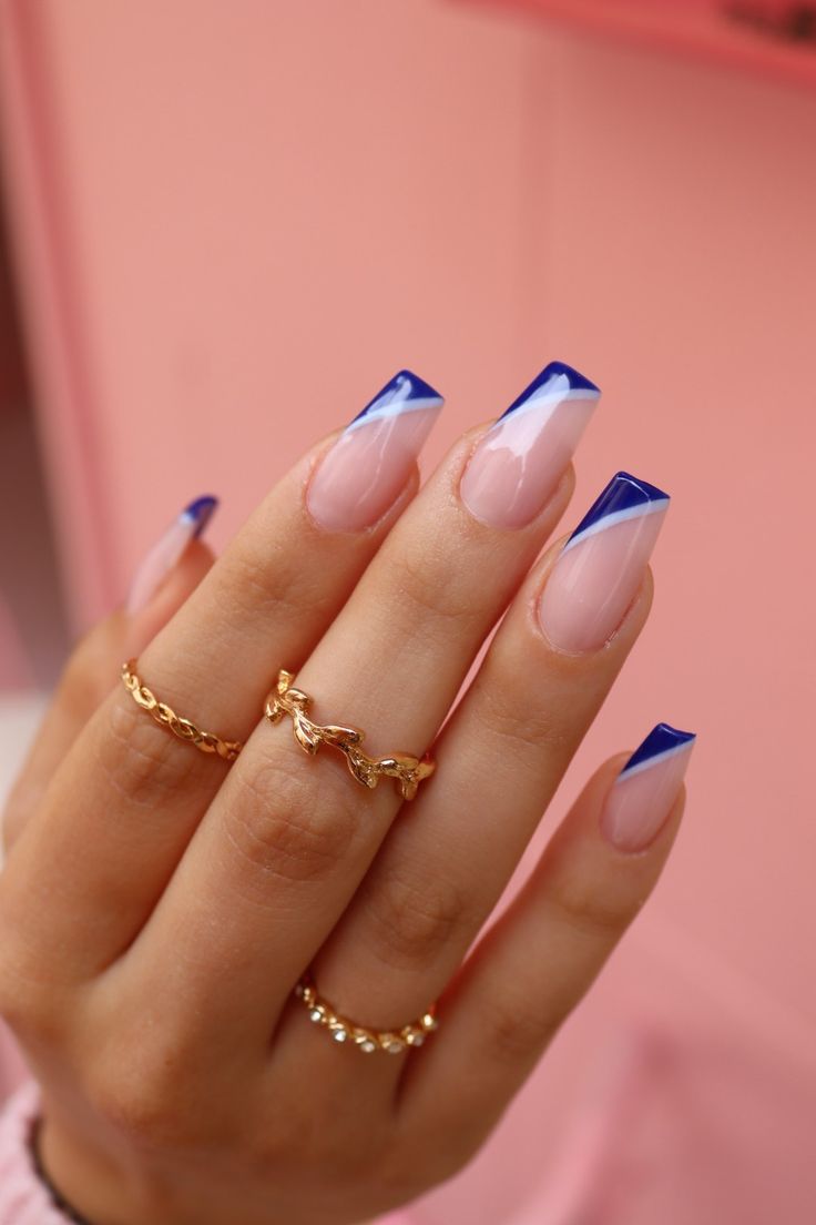 Chic French Tip Nail Design with Nude and Blue Accents, Enhanced by Delicate Gold Rings.