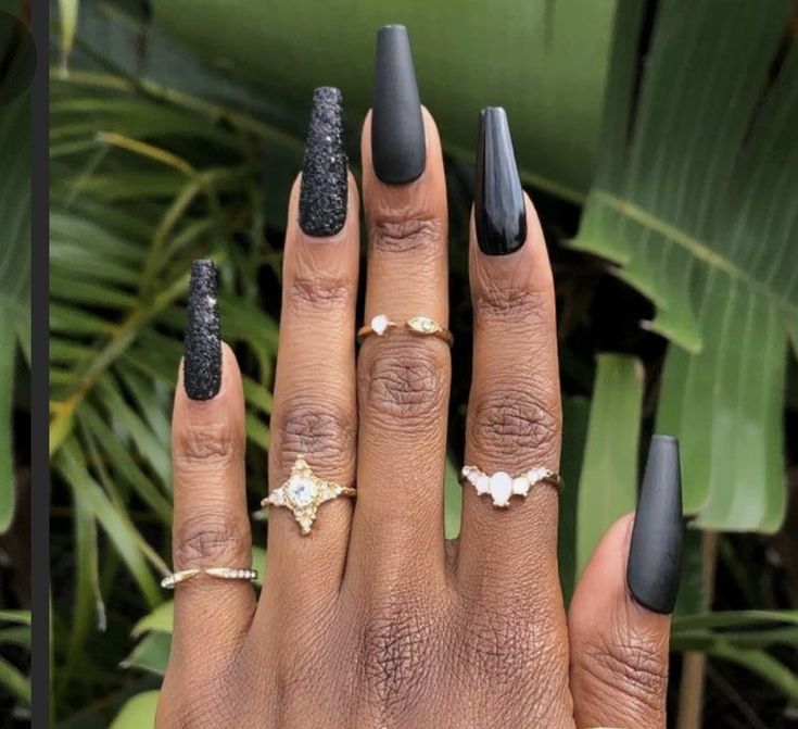 Chic Black Nail Design: Glossy and Matte Textures with Glitter Accents and Gold Rings.