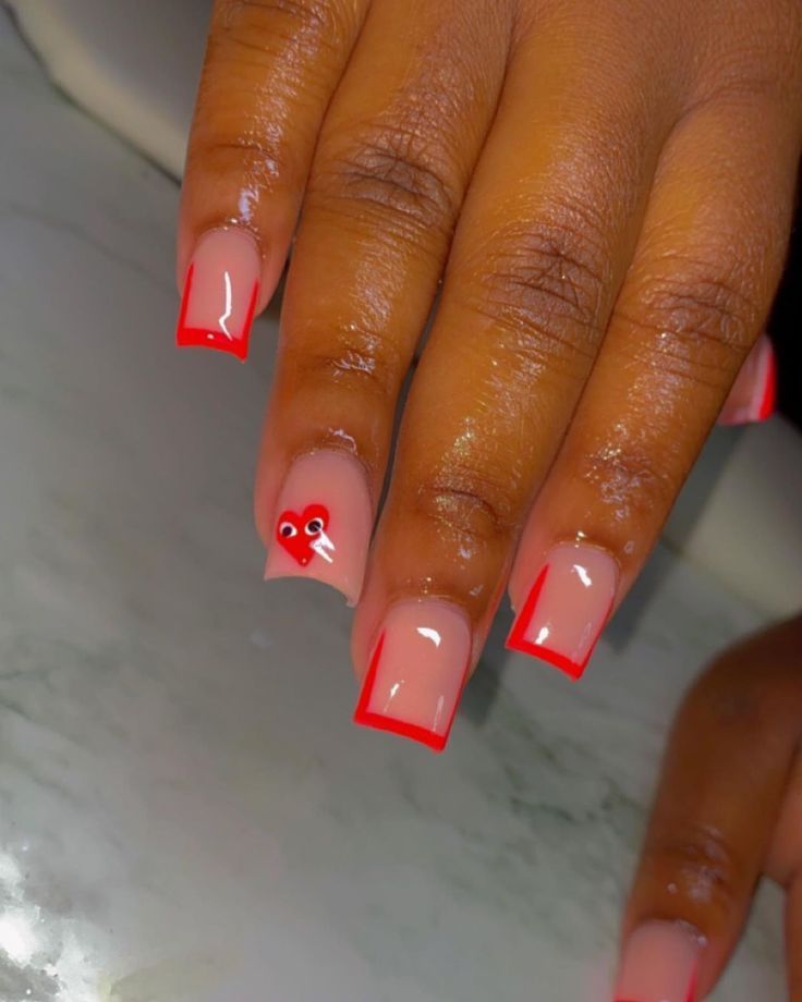 Elegant Nude French Manicure with Striking Red Tips and Heart Accent for a Sophisticated Touch.