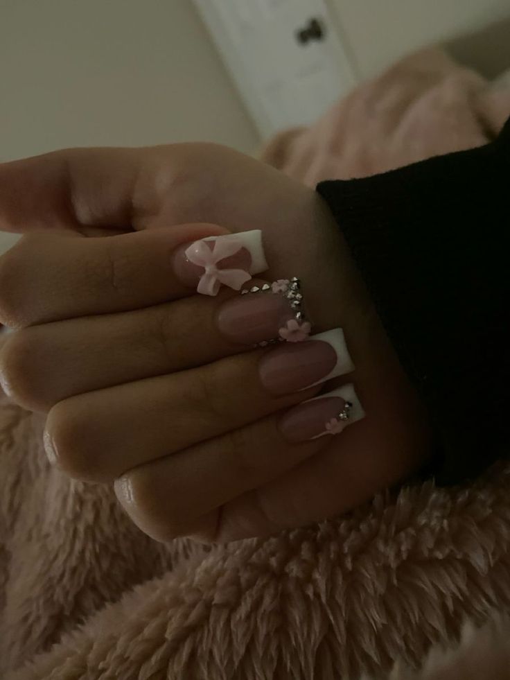 Chic Soft Pink and White Nail Design with Glamorous Bows and Rhinestones.