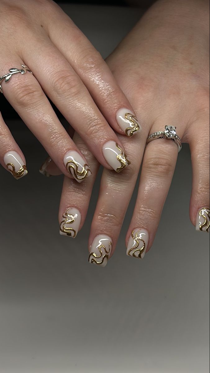 Sophisticated Nail Art: Neutral Base with Wavy Gold Accents and Glossy Finish.