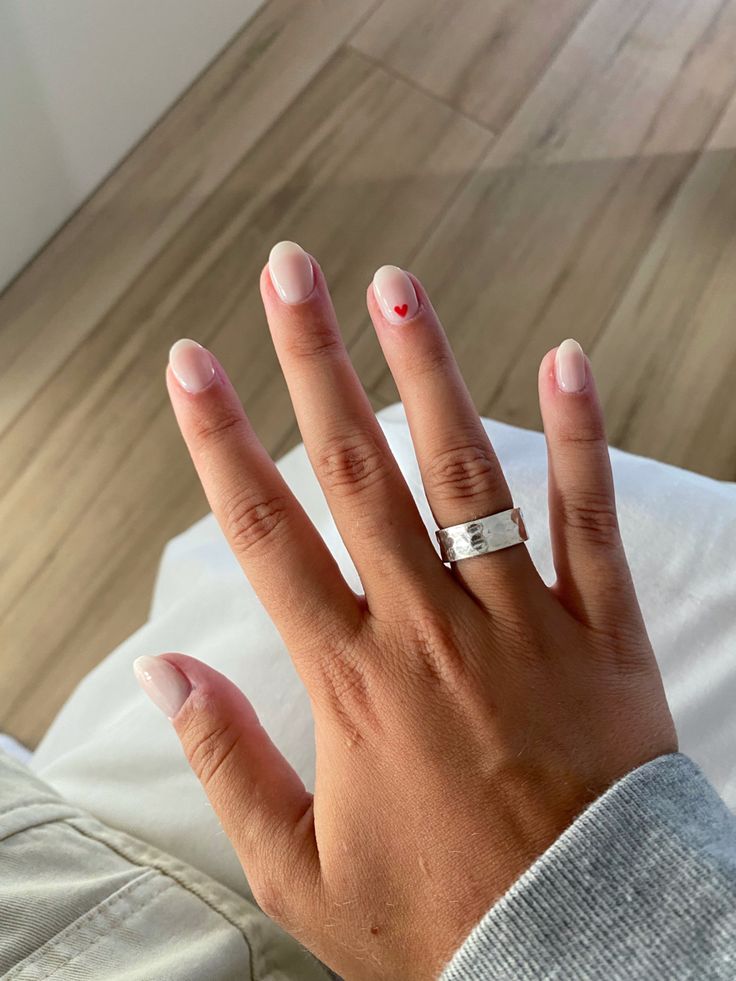 Chic Beige Nail Design with Playful Tiny Red Heart Accents.