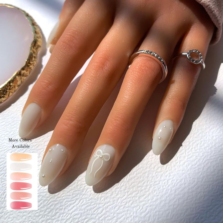 Sophisticated Matte Nude Nails with Pearls and Bow Accents for Understated Elegance.