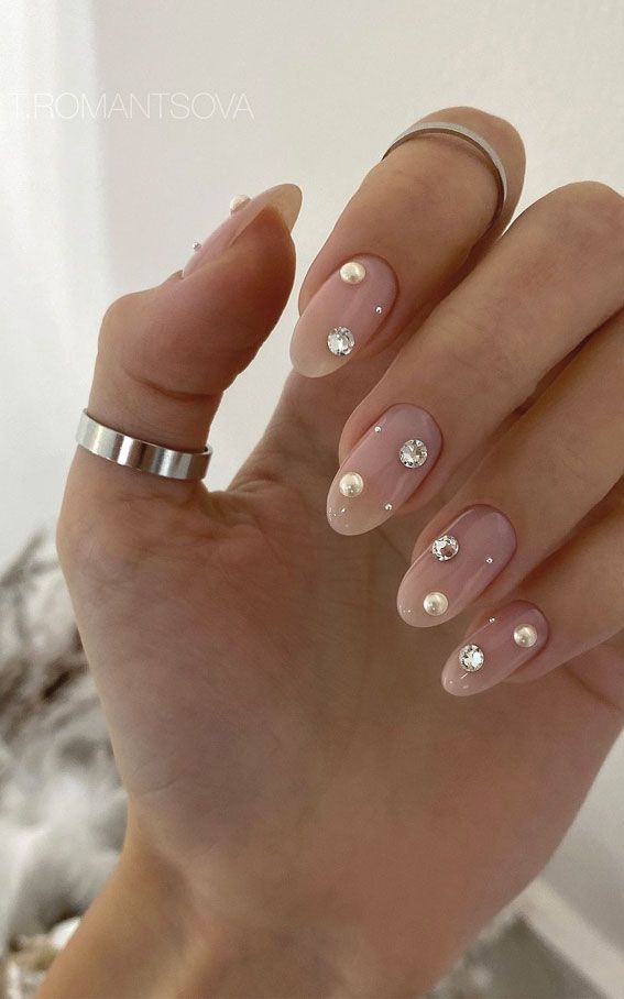 Chic Nude Nail Design with Glossy Finish, Pearls, and Rhinestones for Glamorous Elegance.