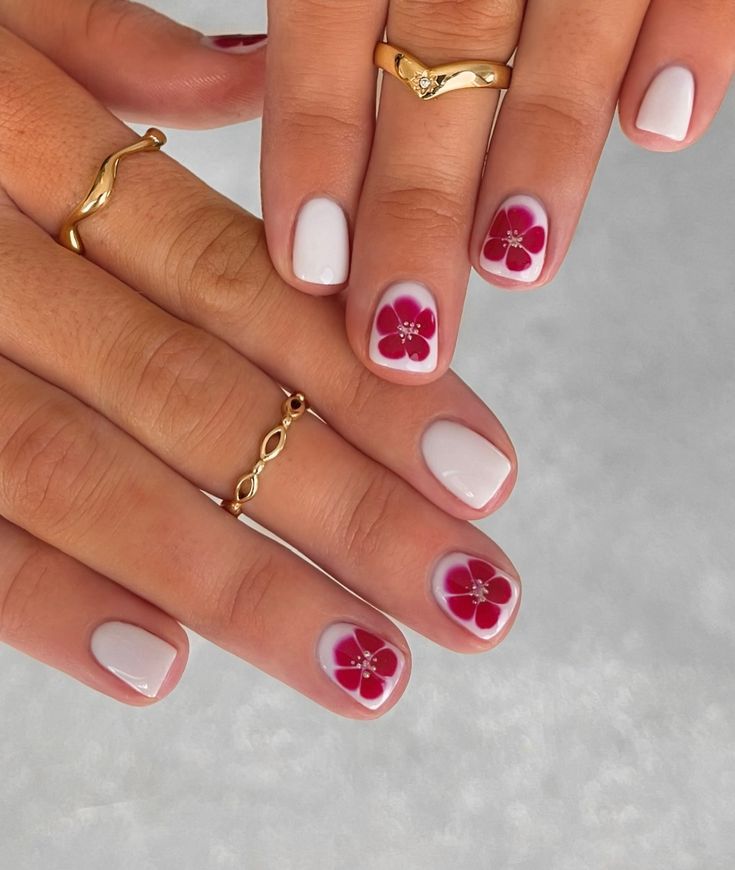 Elegant Floral Nail Design: Vibrant Red Flowers on Soft White Background with Glamorous Coordinated Rings