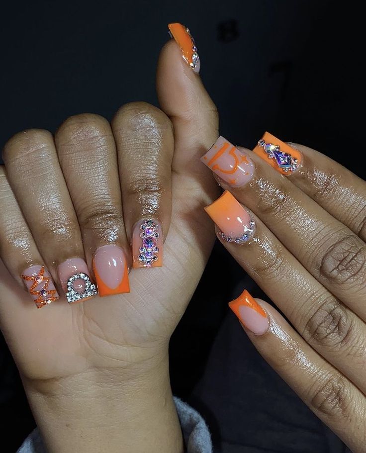 Bold and Glamorous Orange and Nude Nail Design with Intricate Embellishments.