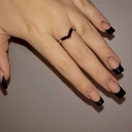 Chic Nail Design: Nude Base with Black Tips and Rhinestone Accents.